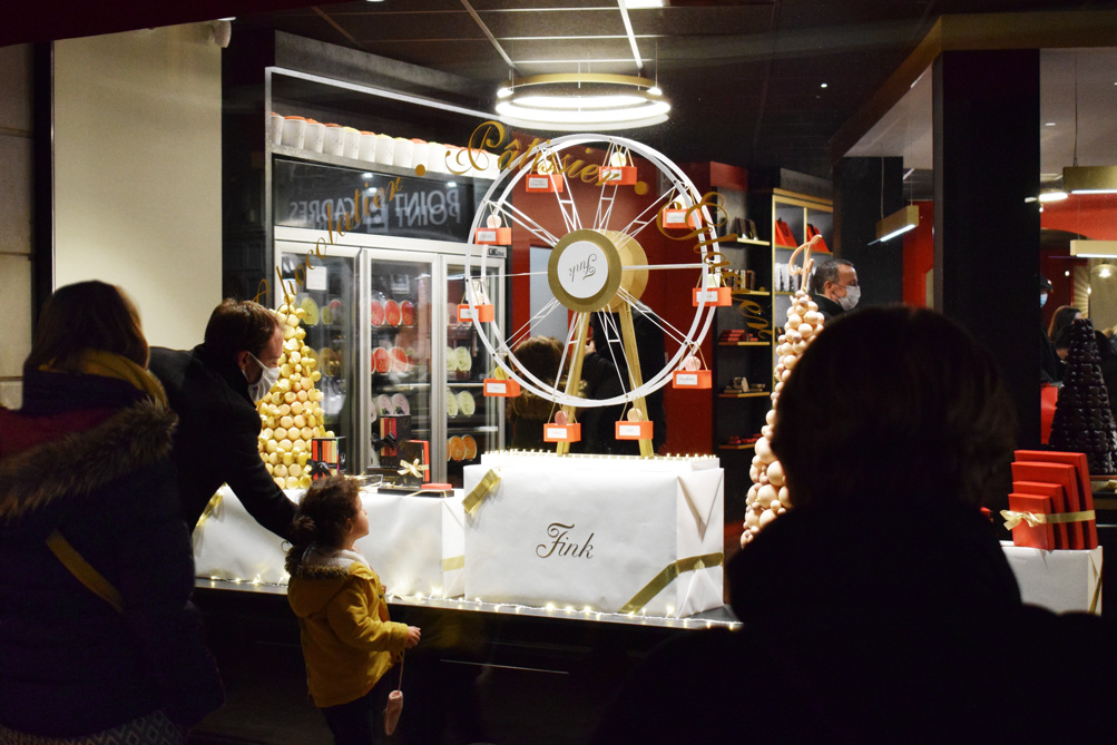 Enfant émerveillé devant la vitrine de Noël animée de la chocolaterie