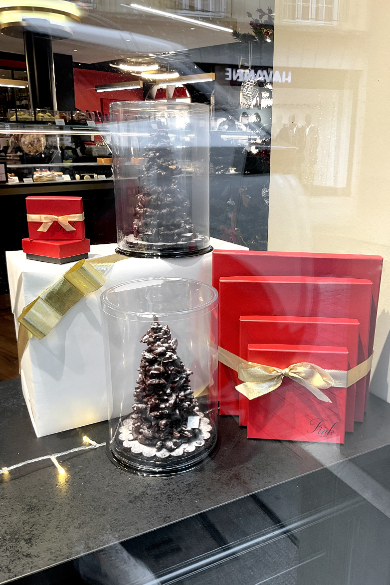 Coffrets et sapins chocolat sur un décor de cadeau blanc et or